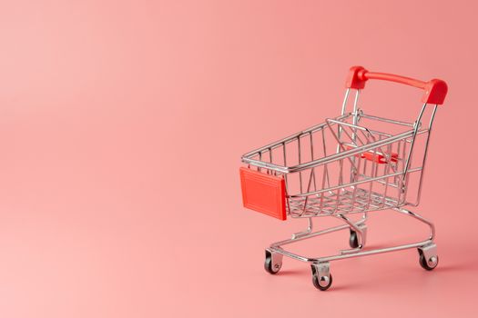 Shopping concept : Red shopping cart on pink background with copy space