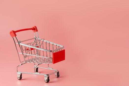 Shopping concept : Red shopping cart on pink background with copy space