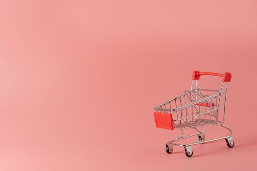 Shopping concept : Red shopping cart on pink background with copy space