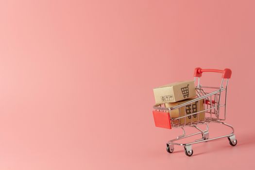 Shopping concept : Cartons or Paper boxes in red shopping cart on pink background. online shopping consumers can shop from home and delivery service. with copy space