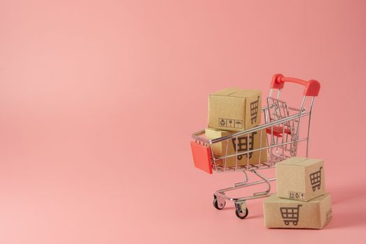 Shopping concept : Cartons or Paper boxes in red shopping cart on pink background. online shopping consumers can shop from home and delivery service. with copy space