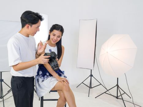 Asian photographers allow models to view pictures taken on the camera screen. The young model is very satisfied with her photo.