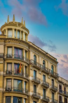 An old hotel or apartment in Barcelona with black wrought iron balconies and spanish flags