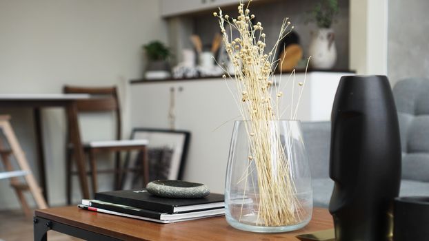 A vase with dry flowers on a table. Scandinavian classic room with wooden and white details, minimalistic interior design. Real photo. Cosy home.