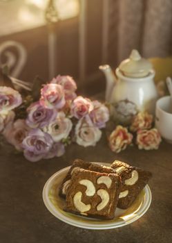 Piece of chocolate cashew nut cake on plate over wooden table