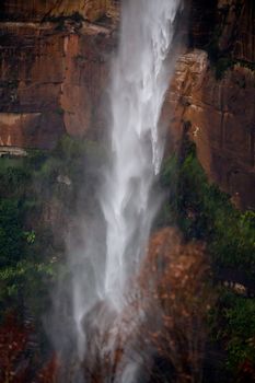 Powerful waterfall tumbling over sandstone cliffs after rain, its movement patterns vary as it falls fast to the bottom