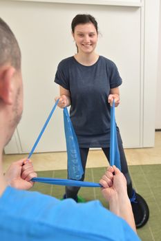 A young male physiotherapist helping a teen girl with stretching exercises 