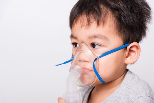 Closeup Asian face, Little children boy sick he using steam inhaler nebulizer mask inhalation oneself on white background, health medical care