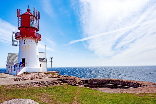 Historic red white lighthouse on the edge of rocky sea coast,  Lindesnes, South Norway