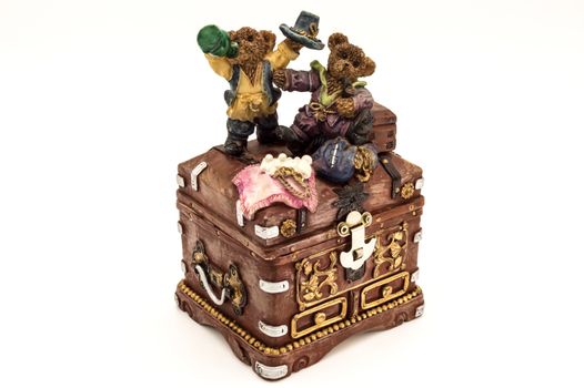 Old treasure chest topped by two little bears on a white background
