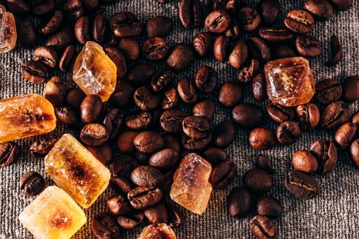 Roasted coffee beans and crystalline sugar scattered on cloth