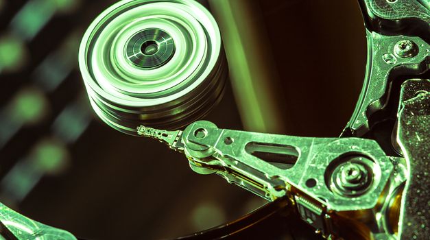 Detail of the inside of a hard disk with the reading head in operation, green light image