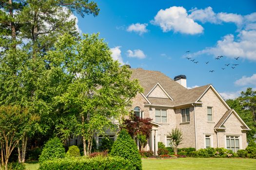 A nice brick house with a landscaped lawn under a summer sky