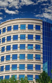 Blue Windows in curved building reflecting sky and clouds