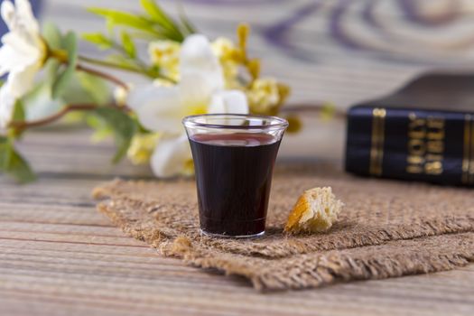 Taking communion concept - the wine and the bread symbols of Jesus Christ blood and body with Holy Bible. Easter Passover and Lord Supper concept Focus on glass.