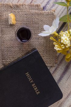 Taking communion concept - the wine and the bread symbols of Jesus Christ blood and body with Holy Bible. Easter Passover and Lord Supper concept Focus on glass.