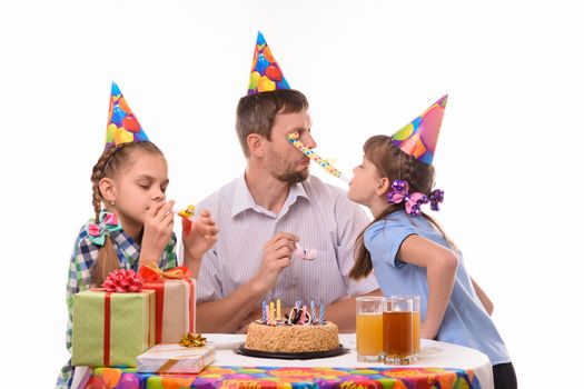 Girl got into the eyes of dad blowing a festive pipe at a birthday party