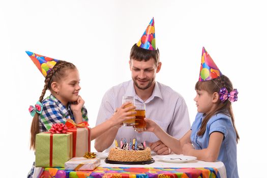 Kids and dad joyfully banging glasses of juice at a birthday party