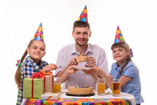 Dad puts the birthday cake on the plates for children