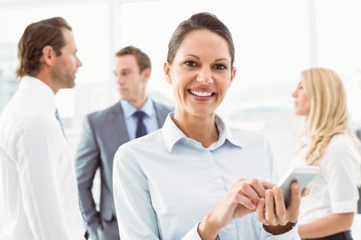 Businesswoman text messaging with colleagues in meeting behind at office