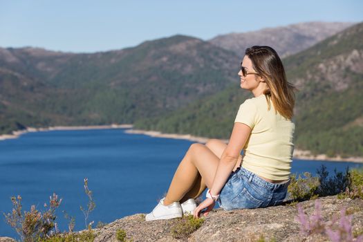 Young happy woman at the mountain, relaxing and enjoying the lake at Geres, Portuguese National Park