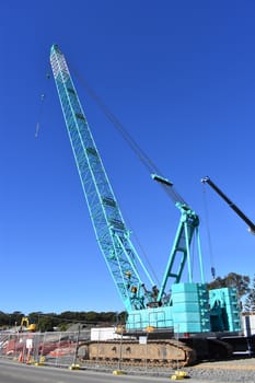 A large blue roller crane on a construction site.