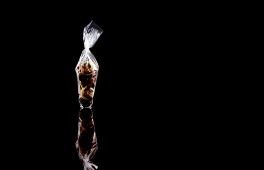 sweets in plastic food packaging with reflection and copy space on black background