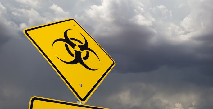 Bio-hazard Yellow Road Sign Against Ominous Stormy Cloudy Sky.