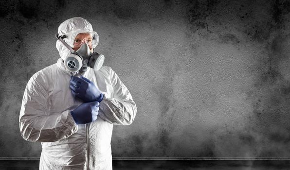 Man Wearing Hazmat Suit, Protective Gas Mask and Goggles Against Dark Wall.