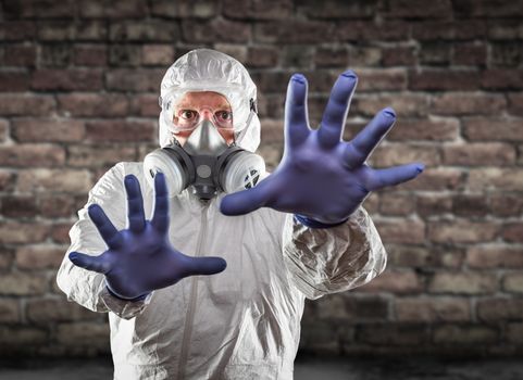 Man Wearing Hazmat Suit, Protective Gas Mask and Goggles Reaching To Stop with Hands.