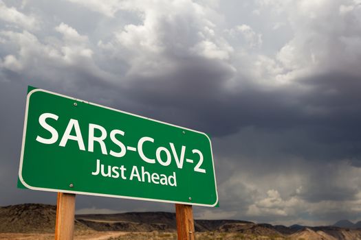 SARS-CoV-2 Coronavirus Green Road Sign Against Ominous Stormy Cloudy Sky.