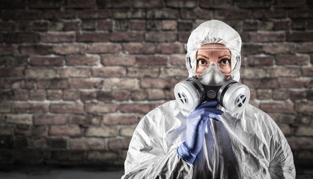 Woman Wearing Hazmat Suit, Protective Gas Mask and Goggles Against Brick Wall.