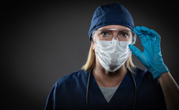 Female Medical Worker Wearing Protective Face Mask and Gear Against Dark Background.