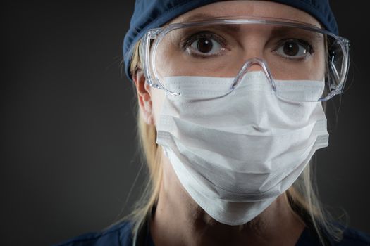 Female Medical Worker Wearing Protective Face Mask and Gear Against Dark Background.