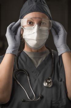 Female Doctor or Nurse Wearing Scrubs, Protective Face Mask and Goggles.