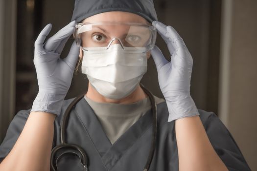 Female Doctor or Nurse Wearing Scrubs, Protective Face Mask and Goggles.