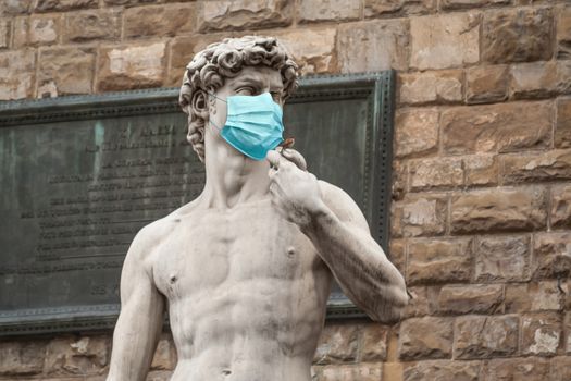 The Statue Of David in the Piazza della Signoria In Italy Wearing Blue Protective Medical Face Mask.