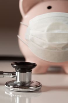 Stethoscope and Piggy Bank Wearing Protective Medical Face Mask.