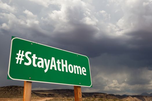 #Stay At Home Green Road Sign Against An Ominous Cloudy Sky.