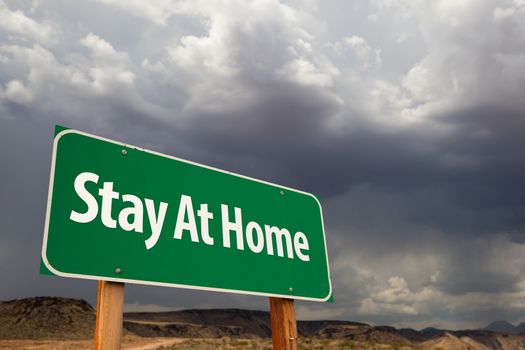 Stay At Home Green Road Sign Against An Ominous Cloudy Sky.