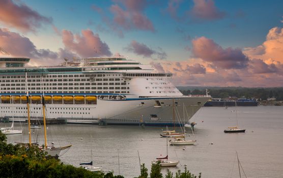 A luxury cruise ship in a harbor with sailboats under foggy conditions