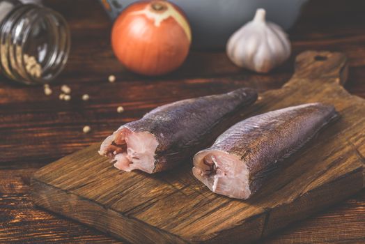 Hake carcasses on cutting board with spices and vegetables