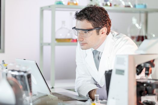 Portrait of a confident male health care professional in his working environment wearing lab coat and goggles. Healthcare and biotechnology concept.