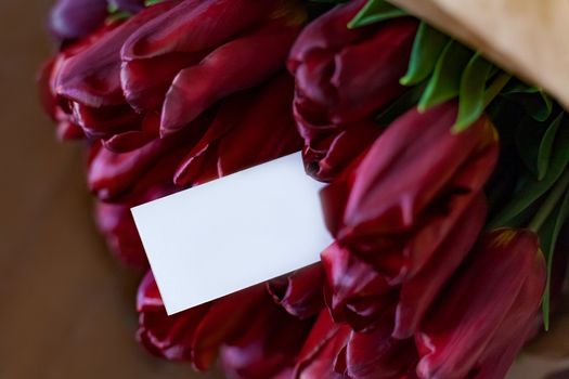 Holiday greeting card among deep red tulip bouquet