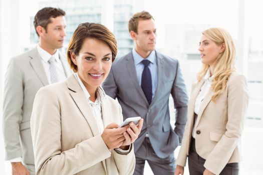 Businesswoman text messaging with colleagues in meeting behind at office