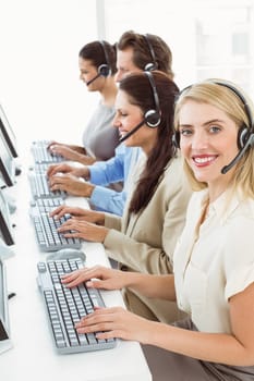 Portrait of young business people with headsets using computers in office