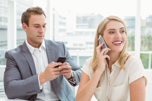 Young business people using mobile phones in office