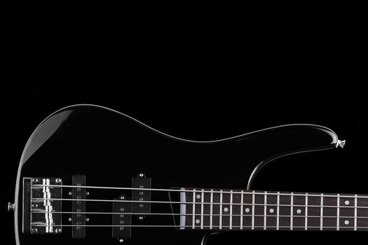 A Black electric bass guitar on black background with copy space