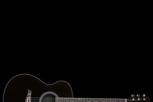 A black guitar on black background with copy space