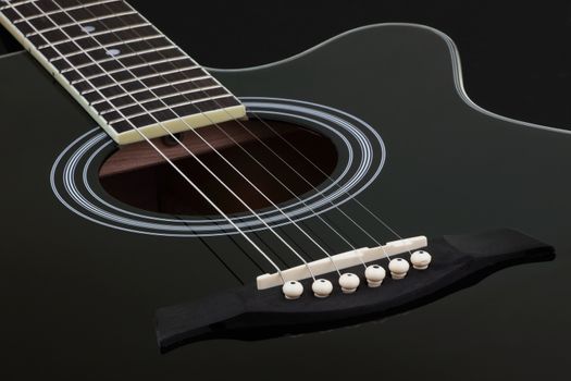 The body of black electric acoustic guitar on dark background